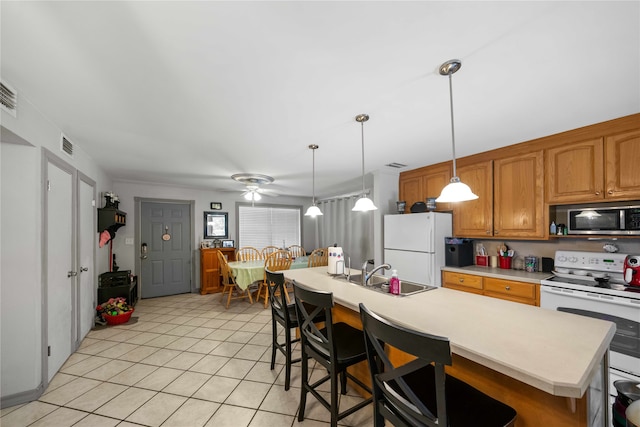 kitchen with white appliances, hanging light fixtures, sink, and a kitchen island with sink