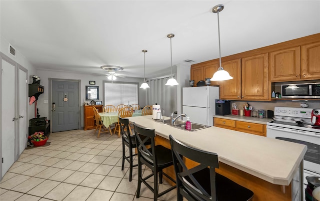 kitchen featuring white appliances, sink, ceiling fan, pendant lighting, and a center island with sink