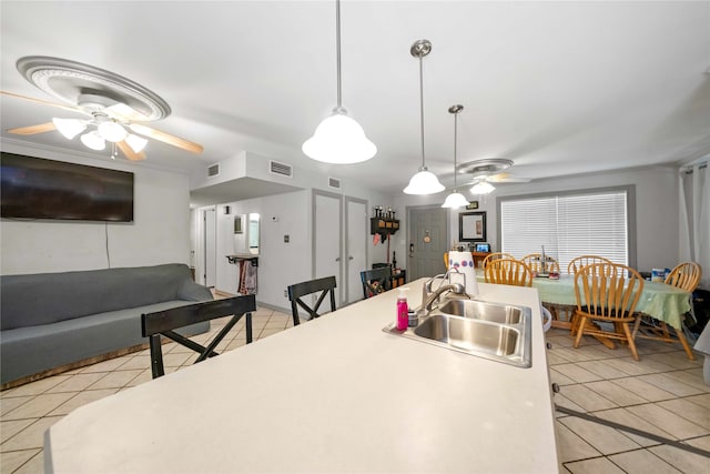 kitchen with hanging light fixtures, sink, light tile patterned floors, and ceiling fan