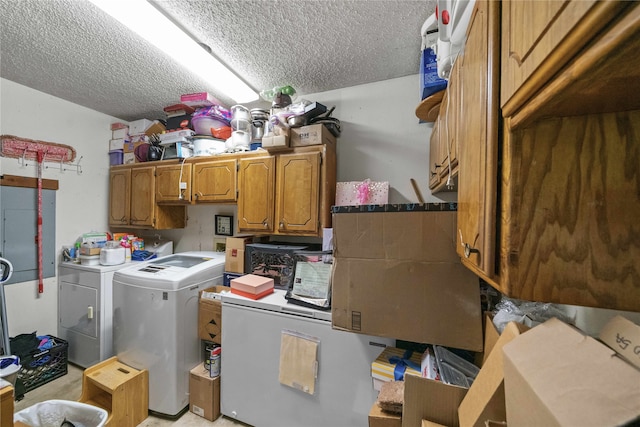 laundry area featuring a textured ceiling, washing machine and clothes dryer, and cabinets