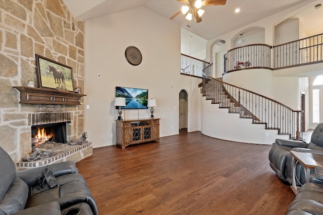 living room featuring dark wood-type flooring, high vaulted ceiling, and a fireplace