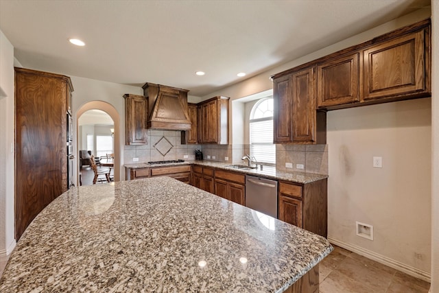 kitchen featuring stone counters, a kitchen island, custom range hood, and stainless steel appliances