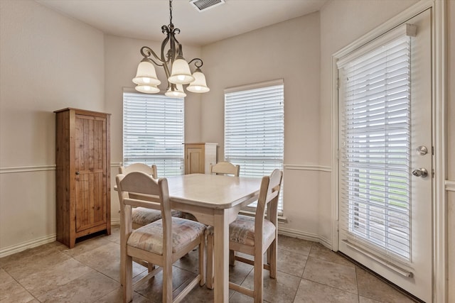 tiled dining room featuring a healthy amount of sunlight and a chandelier