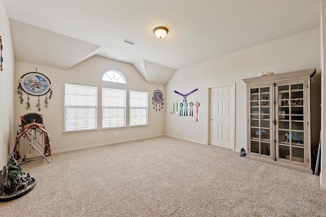 carpeted spare room featuring vaulted ceiling