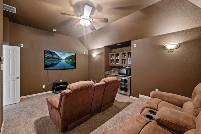 cinema with ceiling fan, light carpet, lofted ceiling, and bar area