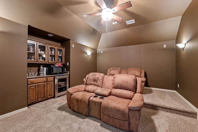 cinema room with wine cooler, vaulted ceiling, light colored carpet, indoor wet bar, and ceiling fan