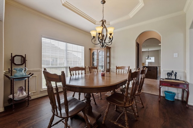 dining room with an inviting chandelier, a tray ceiling, dark wood-type flooring, and crown molding