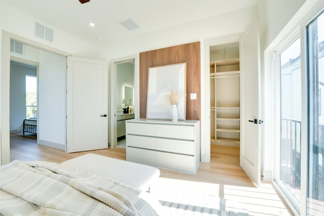 bedroom featuring a walk in closet, light wood-type flooring, and a closet