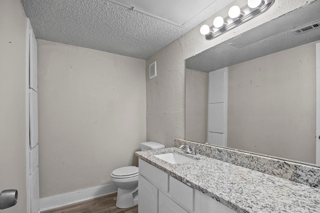 bathroom featuring vanity, toilet, hardwood / wood-style flooring, and a textured ceiling