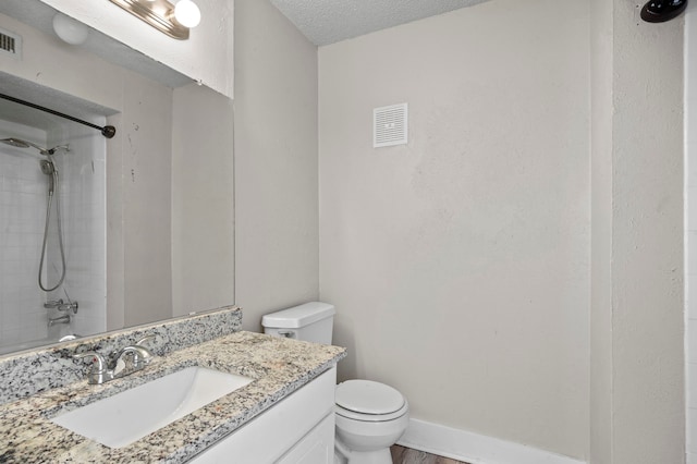 full bathroom with toilet, tiled shower / bath, a textured ceiling, and vanity