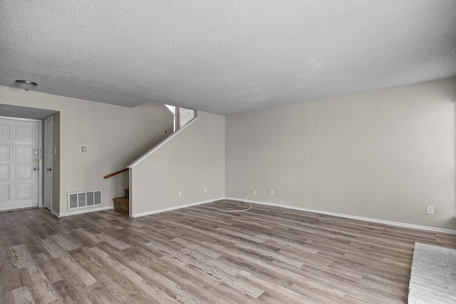 unfurnished living room featuring hardwood / wood-style flooring and a textured ceiling