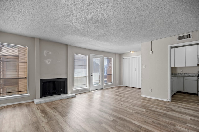 unfurnished living room featuring a textured ceiling and light hardwood / wood-style floors