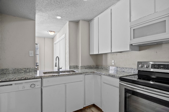 kitchen featuring white cabinets, light stone counters, a textured ceiling, sink, and white appliances