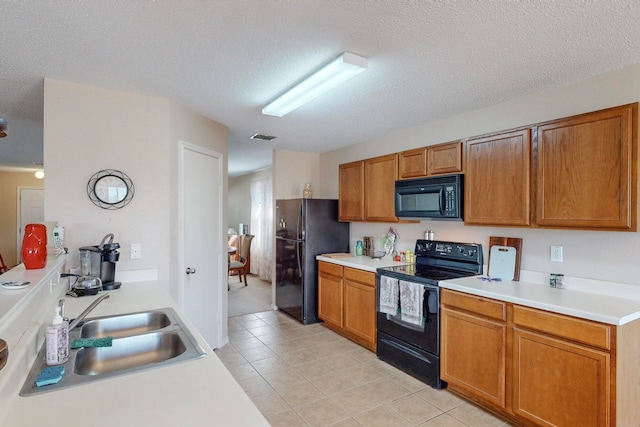 kitchen featuring a textured ceiling, black appliances, sink, and light tile patterned floors