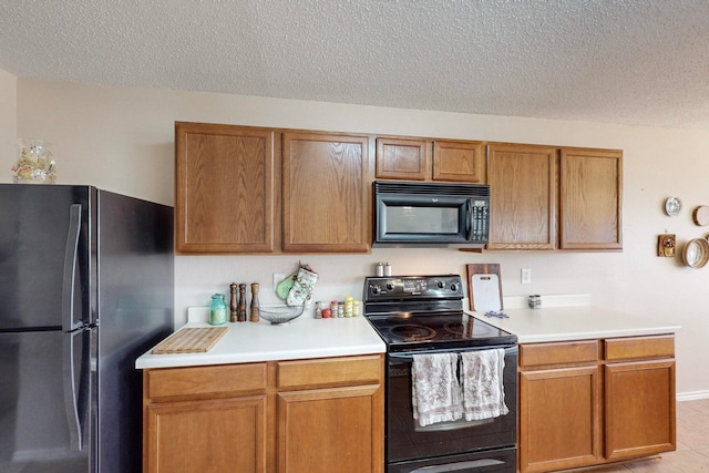 kitchen with light tile patterned floors, black appliances, and a textured ceiling