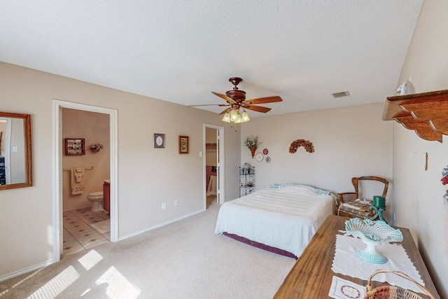 carpeted bedroom featuring ceiling fan, a textured ceiling, and ensuite bath