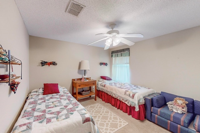 bedroom featuring ceiling fan, light carpet, and a textured ceiling