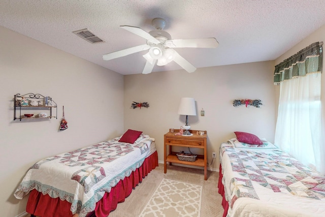 bedroom featuring ceiling fan, a textured ceiling, and light colored carpet