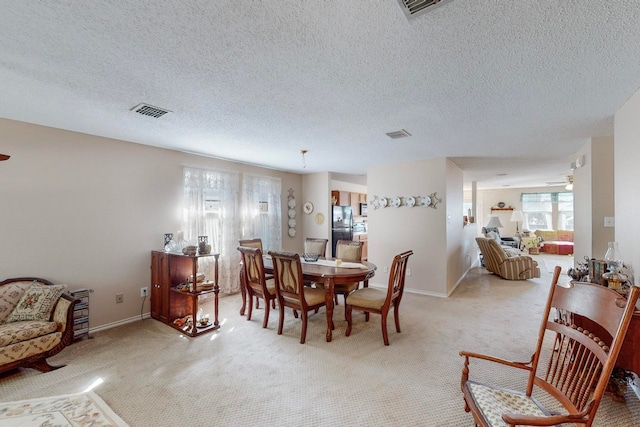 carpeted dining space with a textured ceiling and ceiling fan