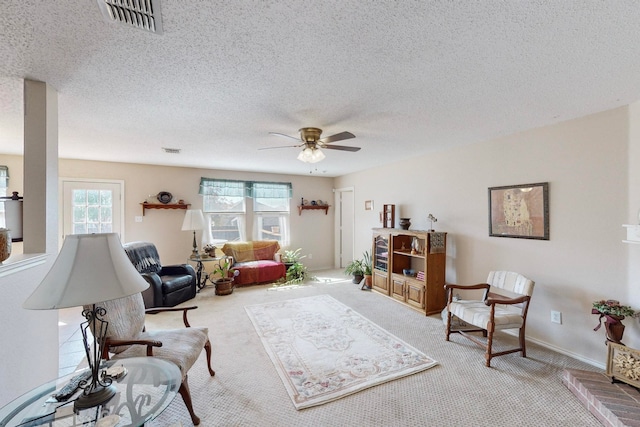 carpeted living room with a textured ceiling and ceiling fan