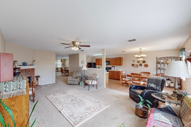 living room with light carpet, a fireplace, a textured ceiling, and ceiling fan with notable chandelier