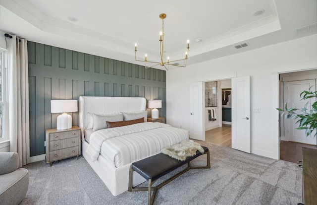 carpeted bedroom with an inviting chandelier and a tray ceiling