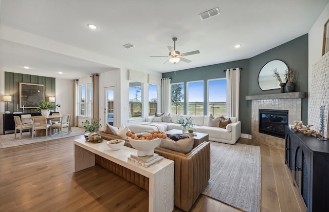 living room featuring ceiling fan, light wood-type flooring, and a fireplace