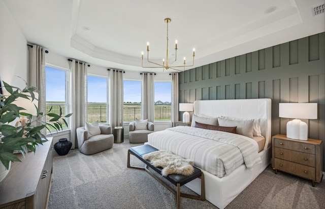 carpeted bedroom featuring a notable chandelier and a tray ceiling