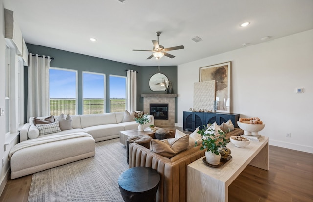 living room featuring ceiling fan, a tile fireplace, and dark hardwood / wood-style flooring