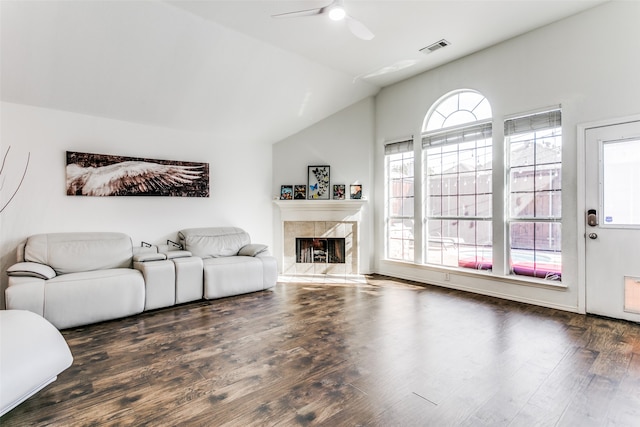 living room with a tiled fireplace, vaulted ceiling, dark hardwood / wood-style floors, and ceiling fan