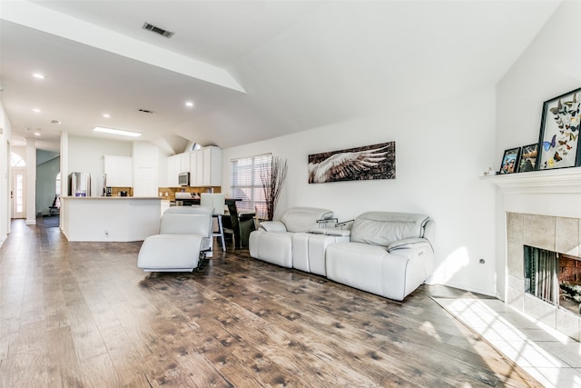 living room with lofted ceiling, dark wood-type flooring, and a tile fireplace