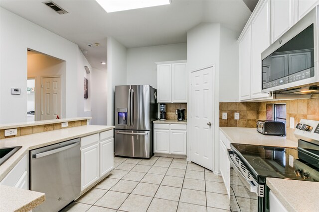 kitchen featuring white cabinetry, backsplash, appliances with stainless steel finishes, and light tile patterned floors