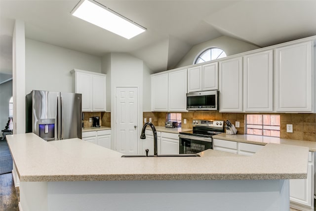 kitchen featuring appliances with stainless steel finishes, sink, white cabinetry, lofted ceiling, and dark hardwood / wood-style floors