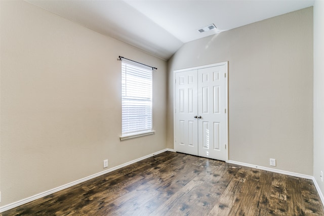 unfurnished bedroom featuring lofted ceiling, dark wood-type flooring, and a closet