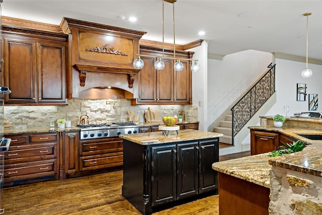 kitchen with decorative light fixtures, crown molding, tasteful backsplash, light stone counters, and stainless steel gas stovetop