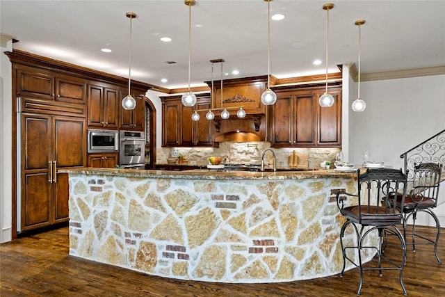 kitchen with crown molding, decorative backsplash, built in appliances, dark wood-type flooring, and dark stone countertops