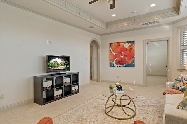 carpeted living room featuring crown molding, a tray ceiling, and ceiling fan