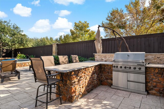 view of patio / terrace featuring an outdoor kitchen, outdoor dry bar, a fenced backyard, and area for grilling