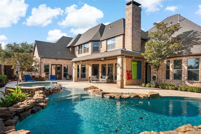 back of house featuring a swimming pool with hot tub and a patio