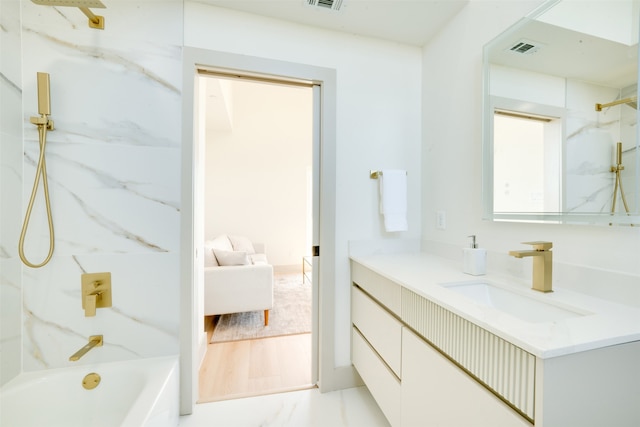 bathroom with hardwood / wood-style flooring, vanity, and tiled shower / bath