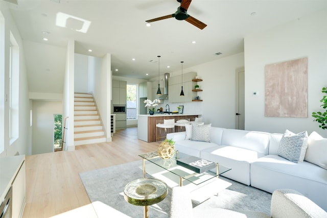 living room featuring ceiling fan, light wood-type flooring, and sink