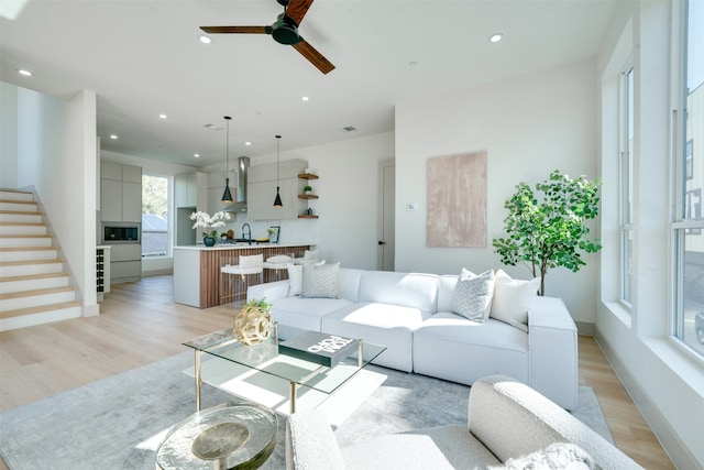 living room featuring light hardwood / wood-style floors, ceiling fan, and sink