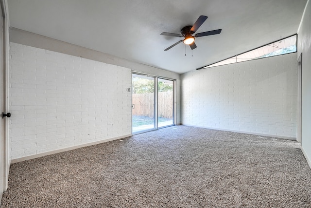 carpeted empty room featuring ceiling fan, lofted ceiling, and brick wall