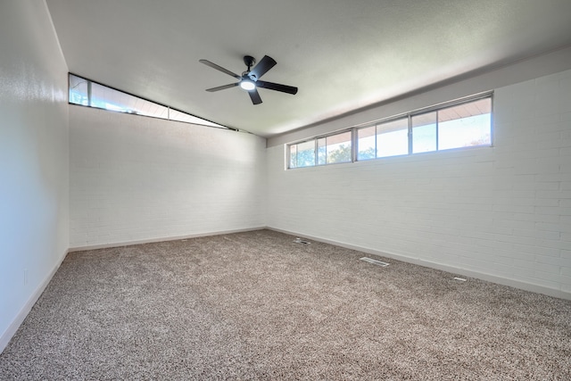 empty room featuring carpet flooring, lofted ceiling, and brick wall