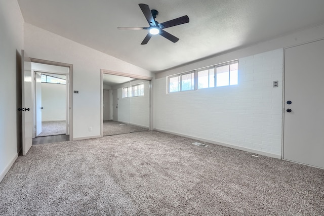 unfurnished bedroom featuring light carpet, ceiling fan, lofted ceiling, and brick wall