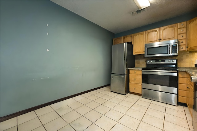 kitchen featuring appliances with stainless steel finishes, light tile patterned floors, and backsplash