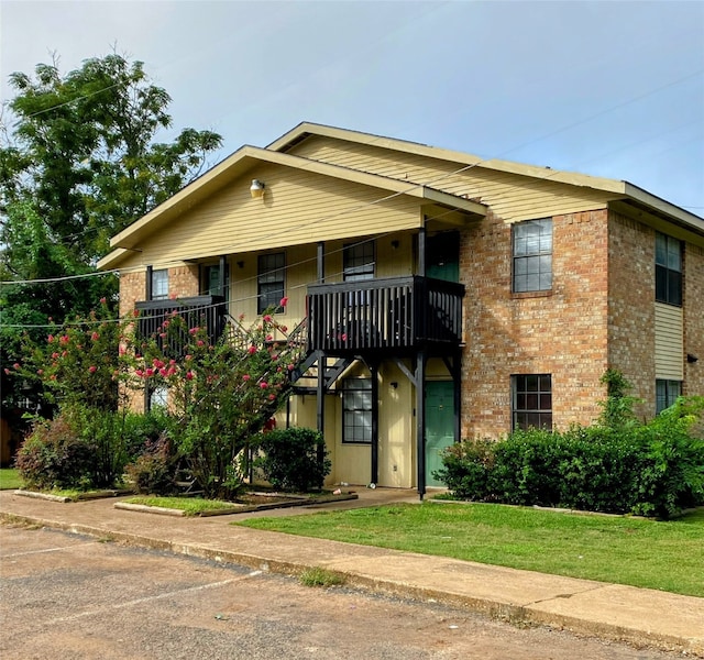 view of front of home featuring a balcony and a front lawn