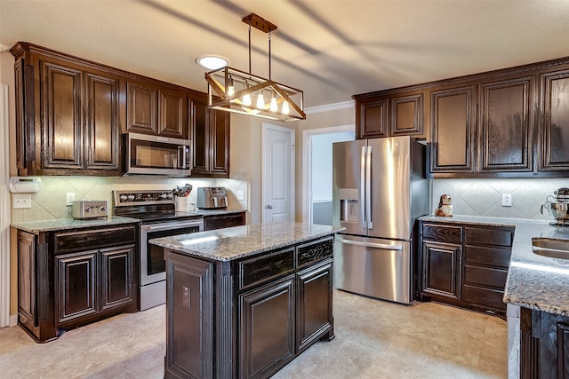 kitchen featuring hanging light fixtures, ornamental molding, light stone countertops, a center island, and appliances with stainless steel finishes