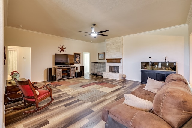 living room with a stone fireplace, ornamental molding, hardwood / wood-style floors, and ceiling fan