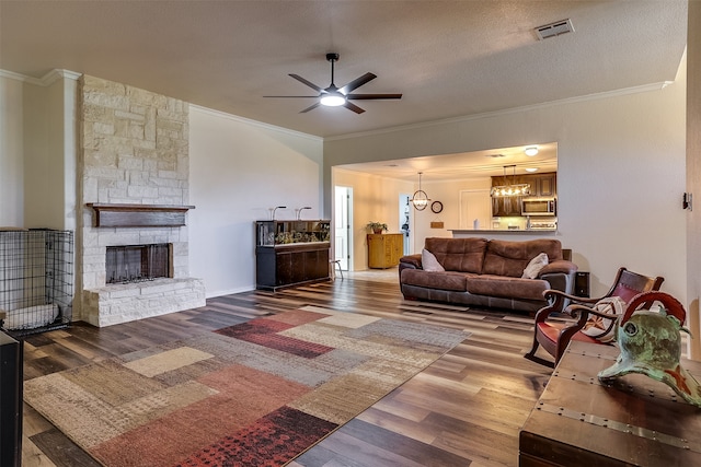 living room with hardwood / wood-style flooring, ornamental molding, and a stone fireplace